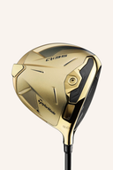 Gold TaylorMade Qi 35 Driver der Designer Series mit schwarzem Griff und glänzender Goldoberfläche, auf einem Golfplatz gestellt