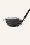 Silberner TaylorMade Qi 35 Designer Series Driver mit schwarzem Griff auf einem Golfplatz.