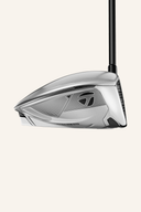 Silberner TaylorMade Qi 35 Designer Series Driver mit schwarzem Griff auf einem Golfplatz.