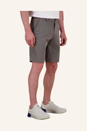 Grauer Herren-Shorts in Khaki-Farbe, getragen von einer Person mit weißem T-Shirt und weißen Sneakern, vor neutralem cremefarbenem Studiohintergrund