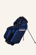Ogio All Elements Hybrid Standbag mit mehreren Fächern und verstellbaren Riemen auf einer Golffläche.