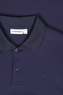 Nahaufnahme eines dunkelblau strukturierten J.Lindeberg Poloshirts (Größe M) mit sichtbarem Marken-Label, Polokragen und Knopfleiste