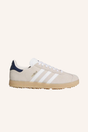 Adidas Gazelle Golfschuhe aus Leder mit grün-weißer Sohle, seitlicher Logo-Details, für Damen und Herren, auf glattem Platz.