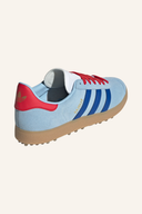 Adidas Gazelle Golfschuhe aus Leder mit griffiger Sohle für Damen und Herren, in Weiß und Blau, auf einem Golfplatz liegend.