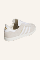 Adidas Gazelle Golfschuhe in Weiß mit grünem Akzent, seitliche Schnürung und griffige Sohle für besseren Halt beim Golf.