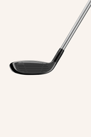 TaylorMade Qi 10 MAX Hybrid mit schwarzer Schlägerkopf und grauem Griff, liegend auf einem weißen Hintergrund.